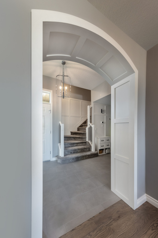 На фото: коридор среднего размера в классическом стиле с серыми стенами, полом из керамической плитки, серым полом и панелями на стенах