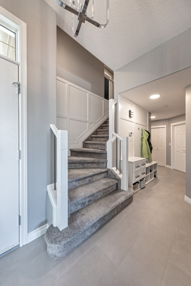 Cette image montre un couloir traditionnel de taille moyenne avec un mur gris, un sol en carrelage de céramique, un sol gris et boiseries.