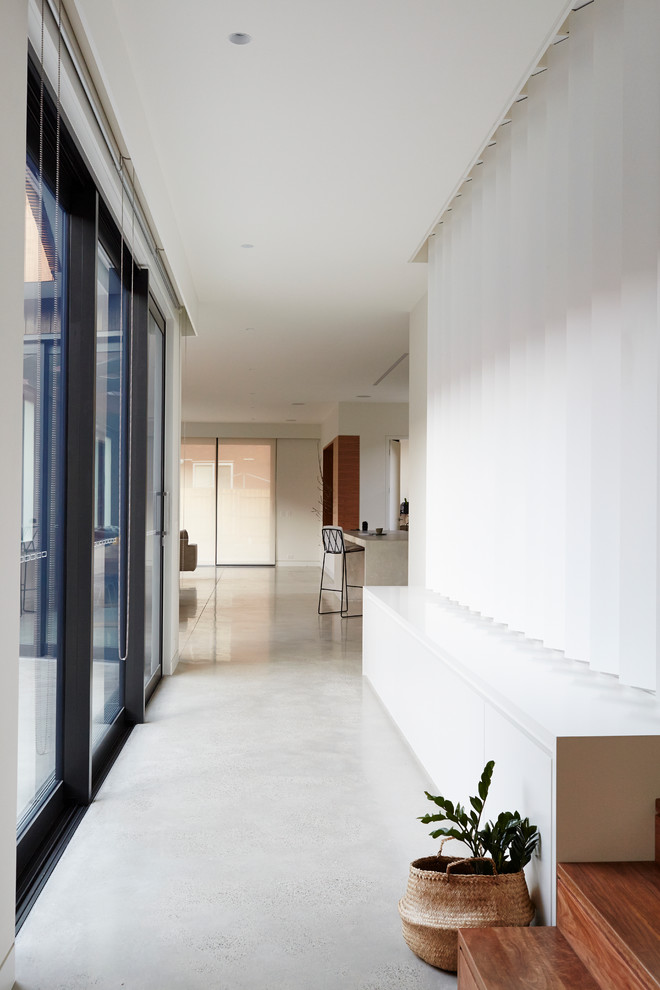 Foto de recibidores y pasillos contemporáneos con paredes blancas y suelo de cemento