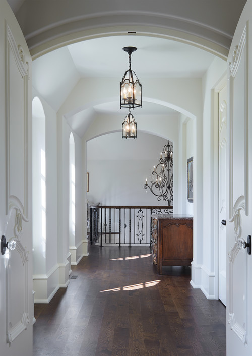 foyer with white walls, archways, pendant lights and dark furniture