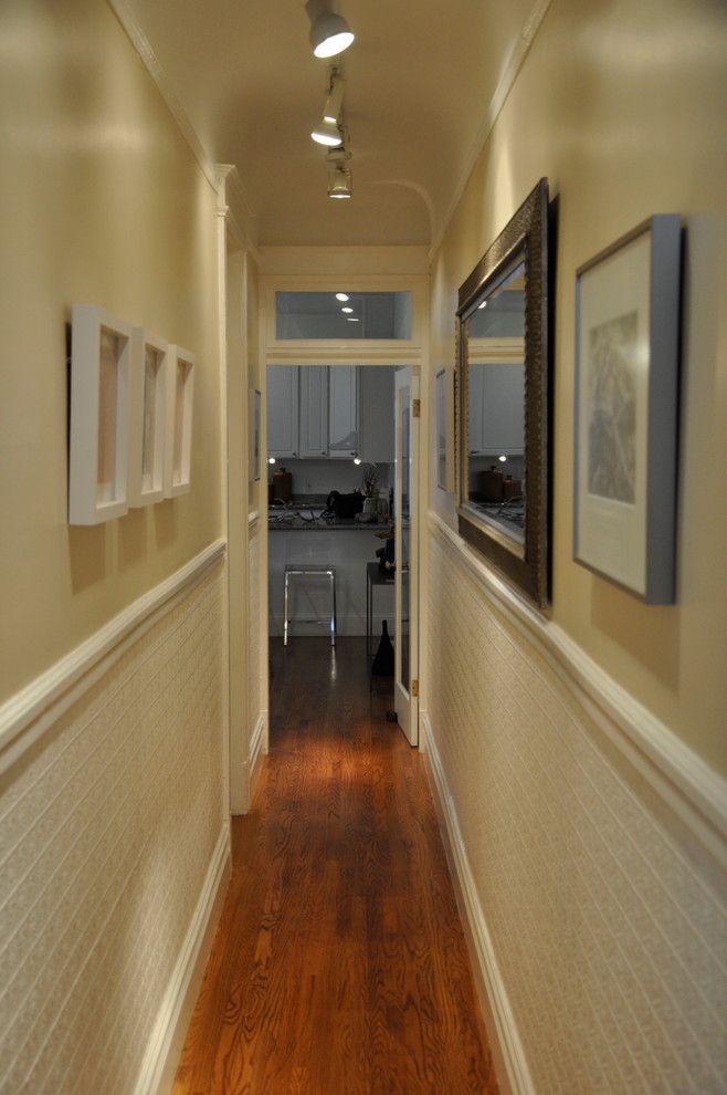 Cette photo montre un couloir tendance avec un mur beige et un sol en bois brun.