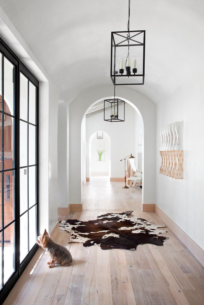 Imagen de recibidores y pasillos mediterráneos con paredes blancas, suelo de madera en tonos medios, suelo beige y iluminación
