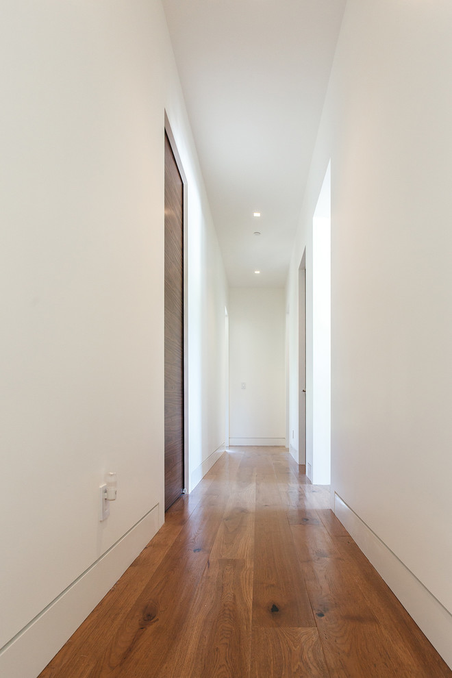 На фото: коридор среднего размера в стиле модернизм с белыми стенами, паркетным полом среднего тона и коричневым полом с