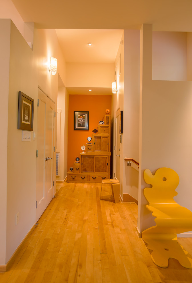 Idée de décoration pour un couloir design avec un mur beige et parquet clair.