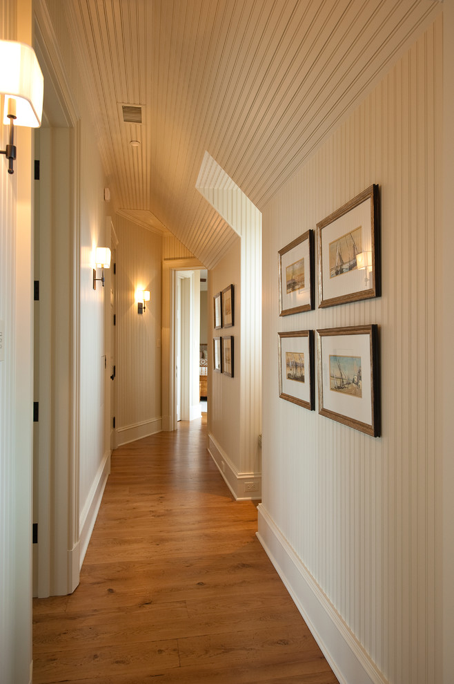Cette image montre un couloir traditionnel de taille moyenne avec un mur blanc et un sol en bois brun.