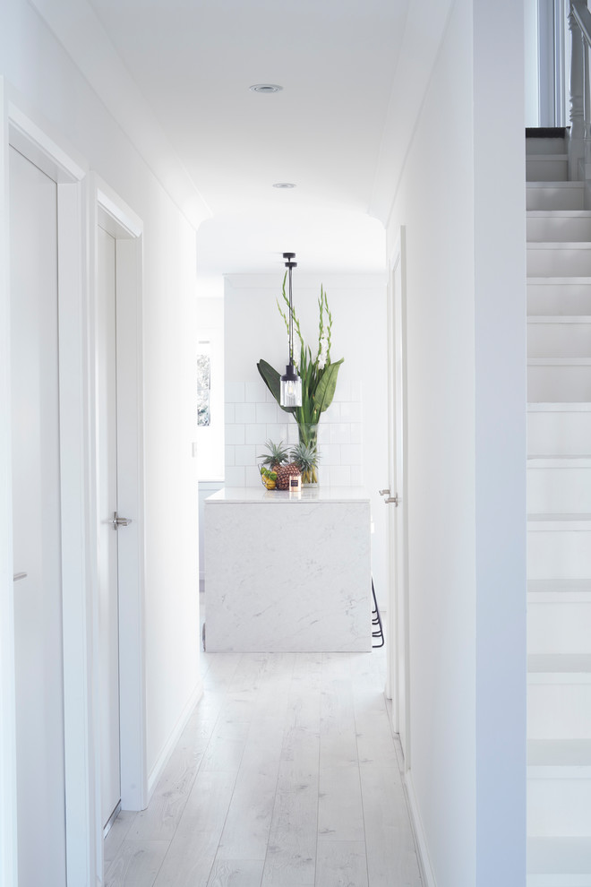 Ispirazione per un ingresso o corridoio minimalista di medie dimensioni con pareti bianche, parquet chiaro e pavimento bianco
