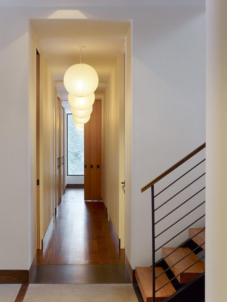 Стильный дизайн: узкий коридор в современном стиле с белыми стенами и темным паркетным полом - последний тренд