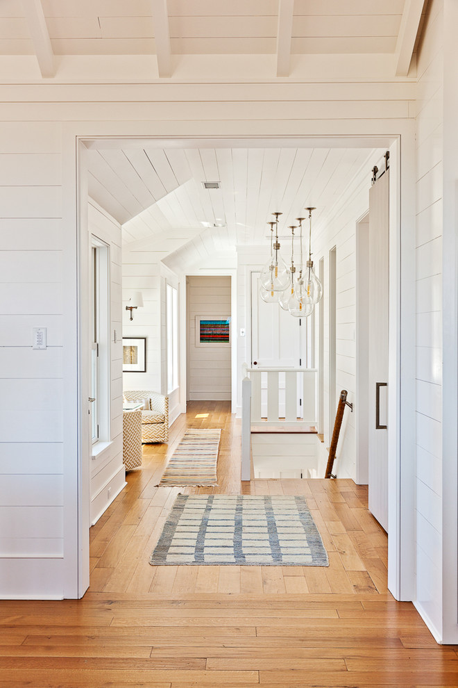 Maritimer Flur mit weißer Wandfarbe und braunem Holzboden in Charleston