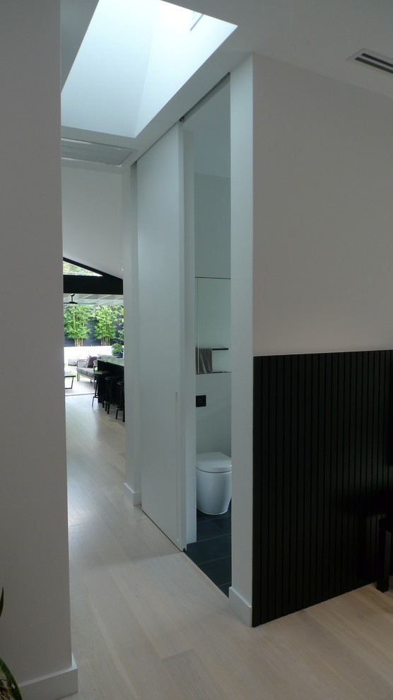 На фото: коридор среднего размера в стиле модернизм с белыми стенами, деревянным полом и белым полом с