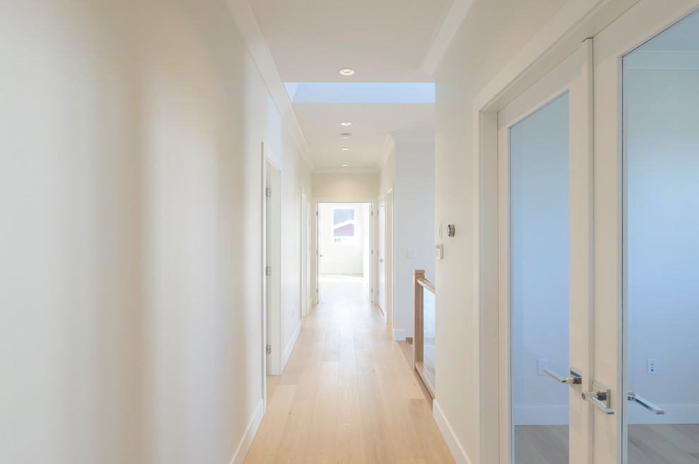 На фото: коридор в стиле неоклассика (современная классика) с белыми стенами и светлым паркетным полом