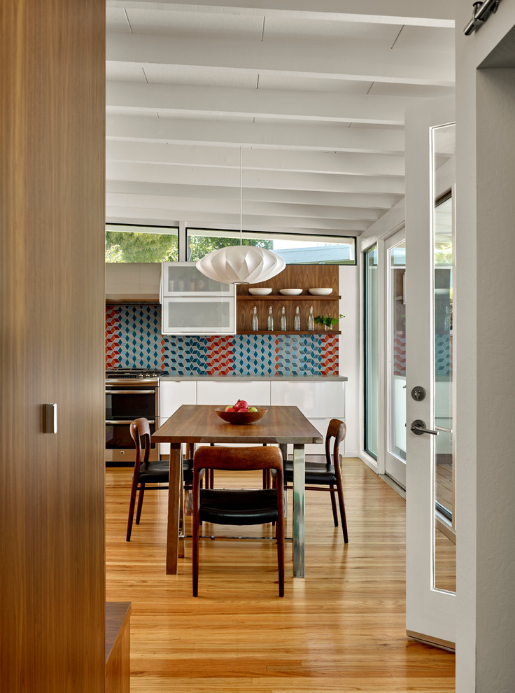 Medium sized midcentury dining room in San Francisco with white walls and medium hardwood flooring.