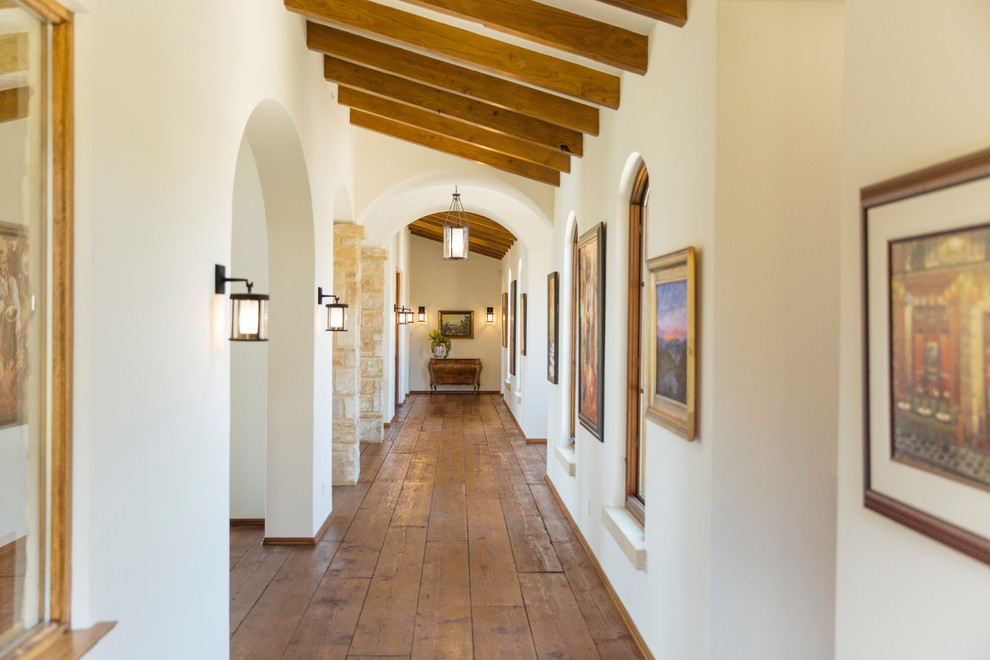 Diseño de recibidores y pasillos mediterráneos con paredes blancas, suelo de madera en tonos medios y suelo marrón