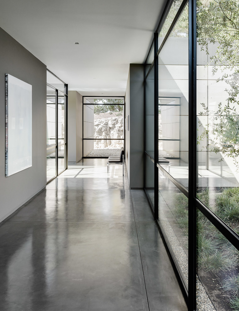 На фото: огромный коридор в современном стиле с серыми стенами, бетонным полом и серым полом с