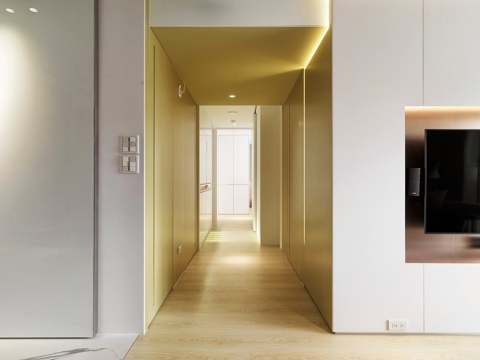 Cette image montre un couloir design de taille moyenne avec un mur jaune et un sol en contreplaqué.