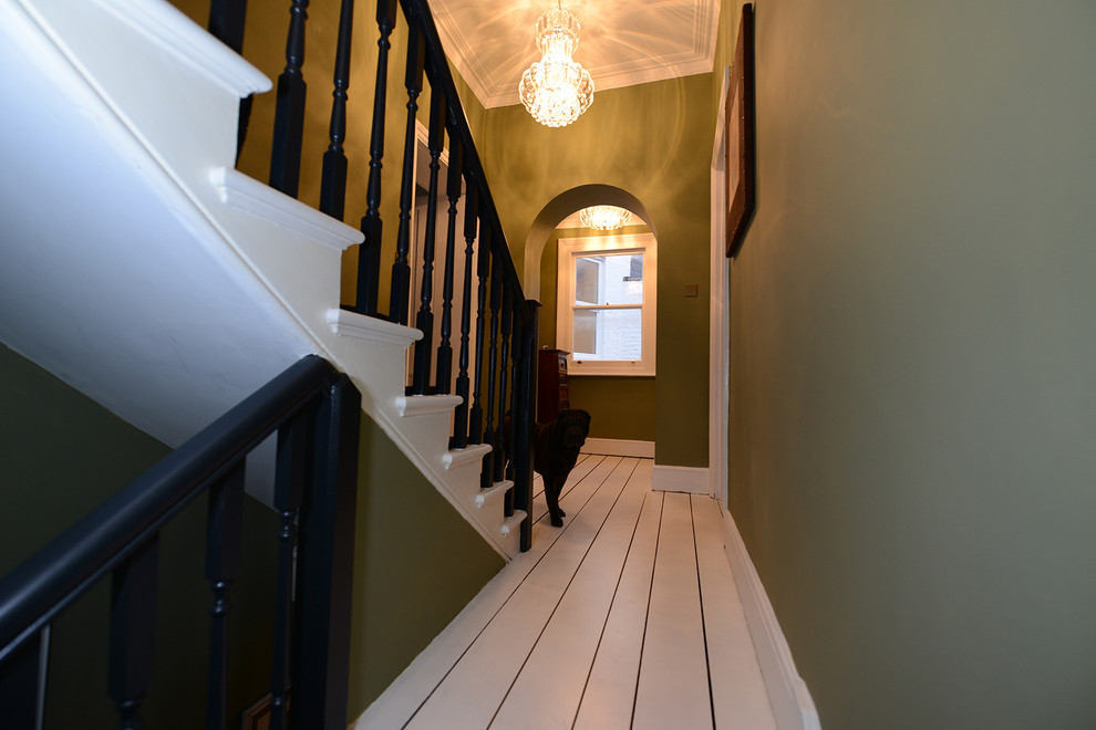 Large transitional painted wood floor and white floor hallway photo in London with green walls