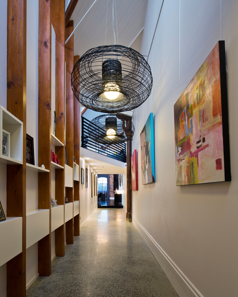 Стильный дизайн: большой, узкий коридор в стиле лофт с бетонным полом, белыми стенами и серым полом - последний тренд