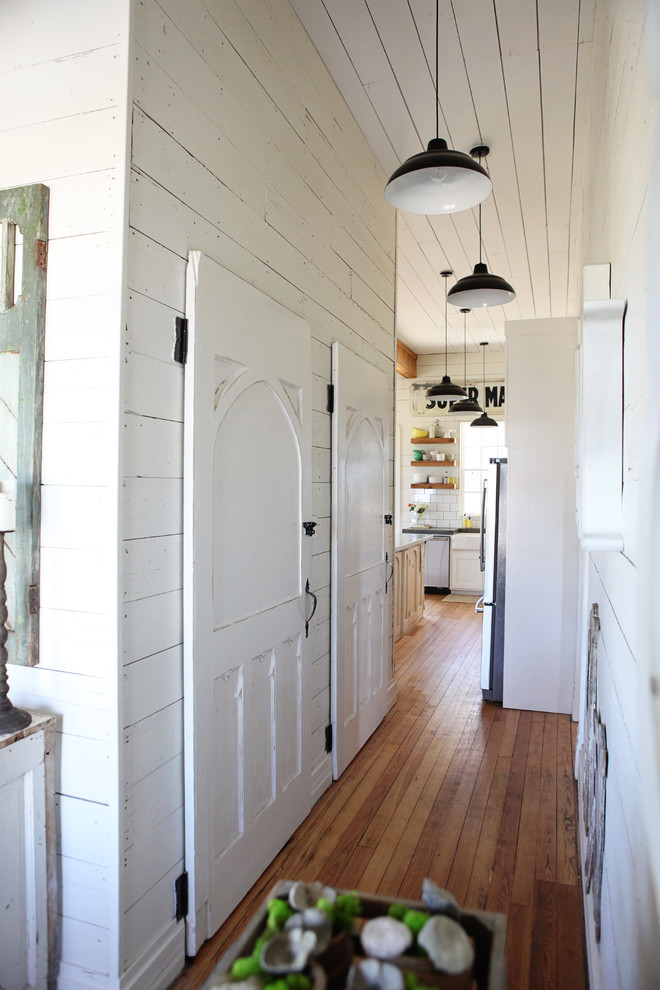 Ejemplo de recibidores y pasillos de estilo de casa de campo con paredes blancas, suelo de madera en tonos medios y iluminación