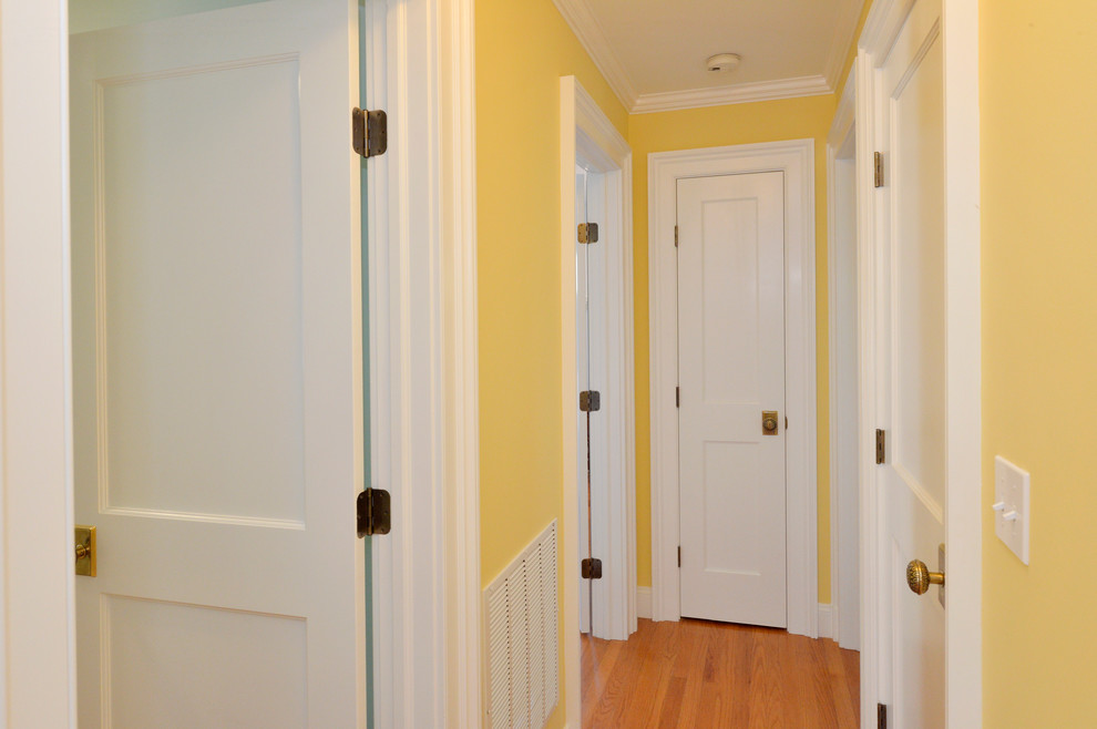 Cette photo montre un petit couloir chic avec un mur jaune et parquet clair.