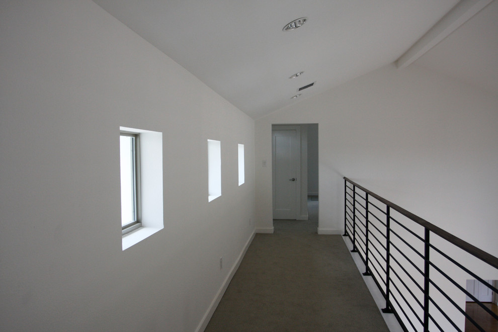 Aménagement d'un très grand couloir contemporain avec un mur blanc et moquette.