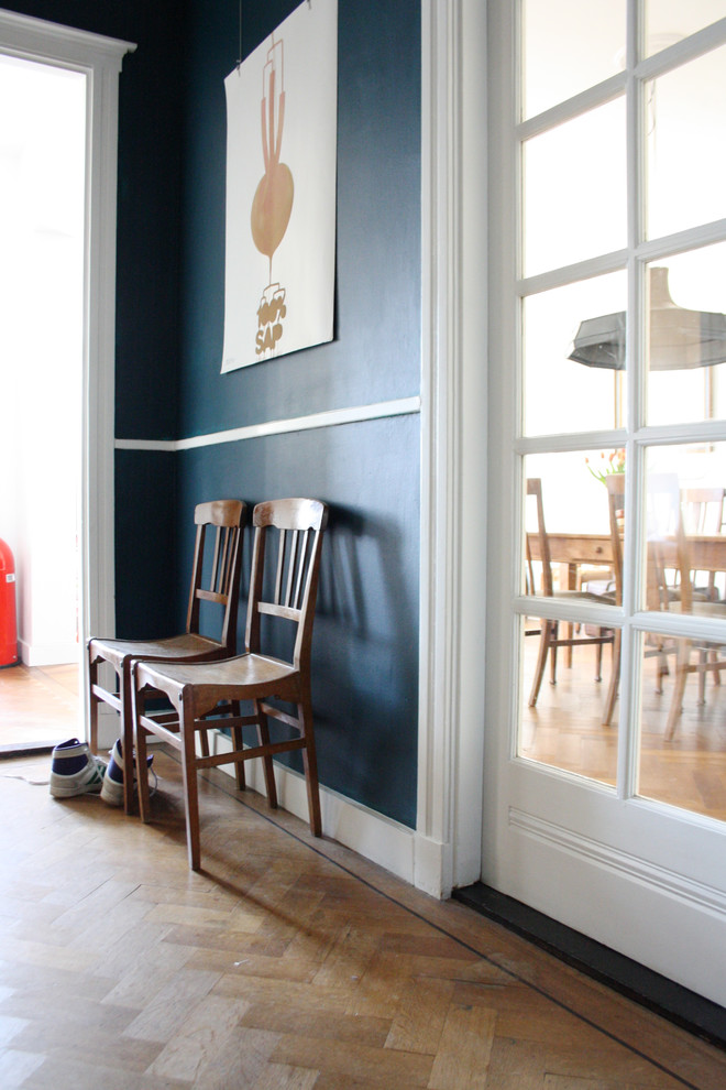 Cette image montre un couloir bohème avec un mur bleu et un sol en bois brun.