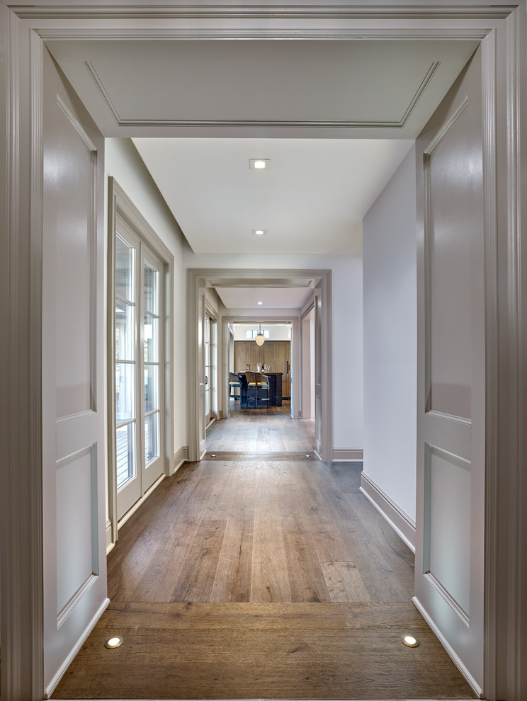Esempio di un grande ingresso o corridoio country con pareti bianche, pavimento in legno massello medio e pavimento marrone