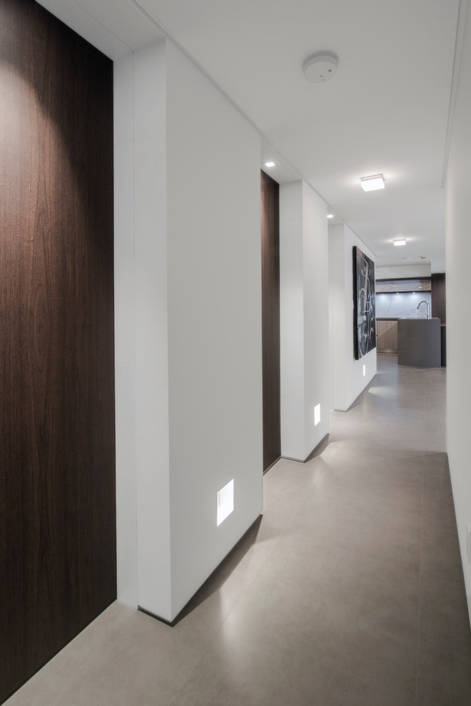 Aménagement d'un couloir moderne avec un mur blanc et sol en béton ciré.