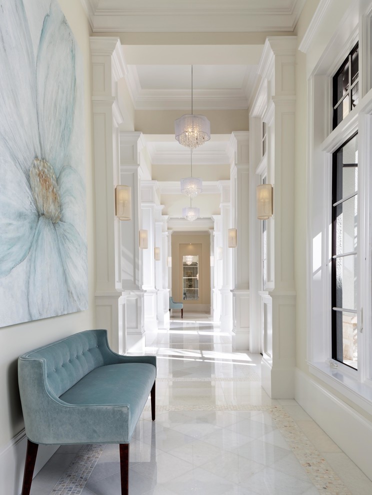 На фото: большой коридор в стиле неоклассика (современная классика) с белыми стенами, мраморным полом и белым полом