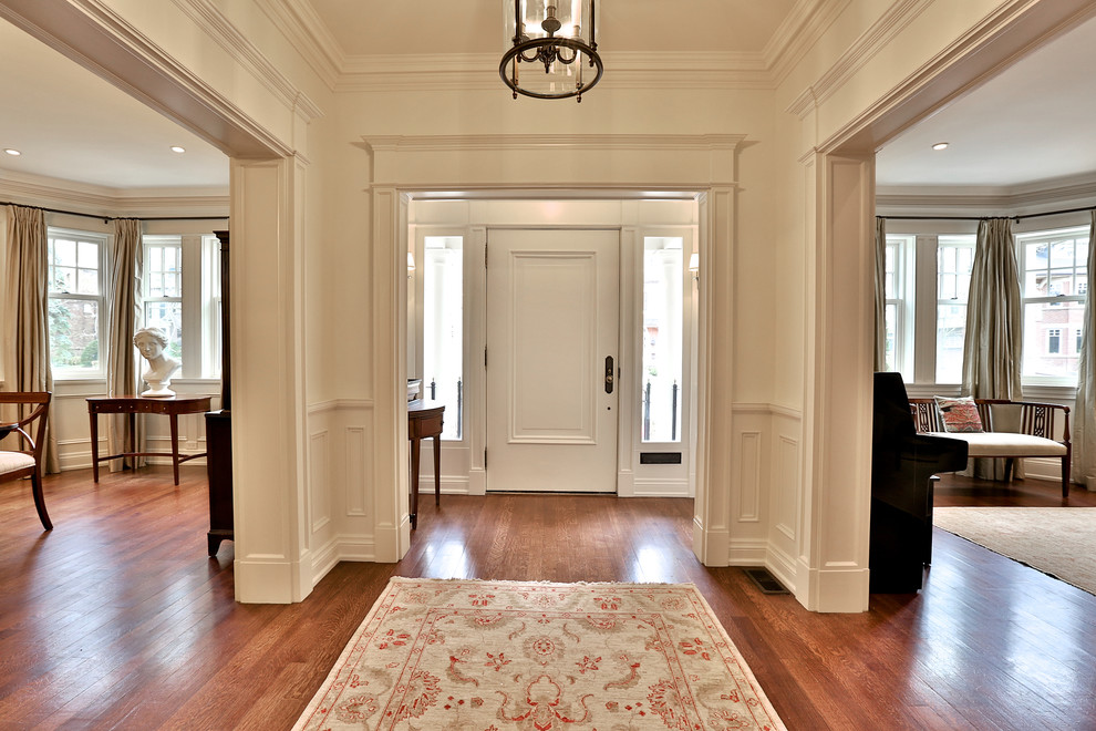 Ejemplo de recibidores y pasillos clásicos renovados extra grandes con paredes blancas, suelo de madera en tonos medios y suelo blanco