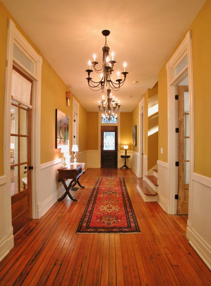 Стильный дизайн: огромный коридор: освещение в викторианском стиле с желтыми стенами, паркетным полом среднего тона и коричневым полом - последний тренд