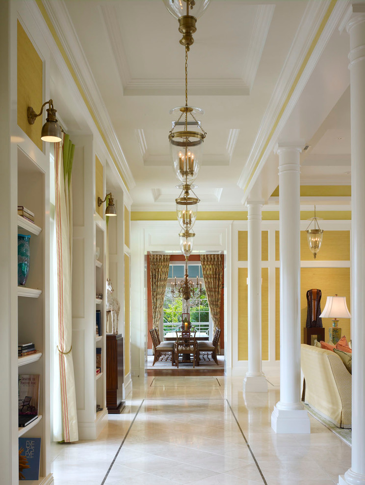Aménagement d'un grand couloir classique avec un mur jaune et un sol en marbre.