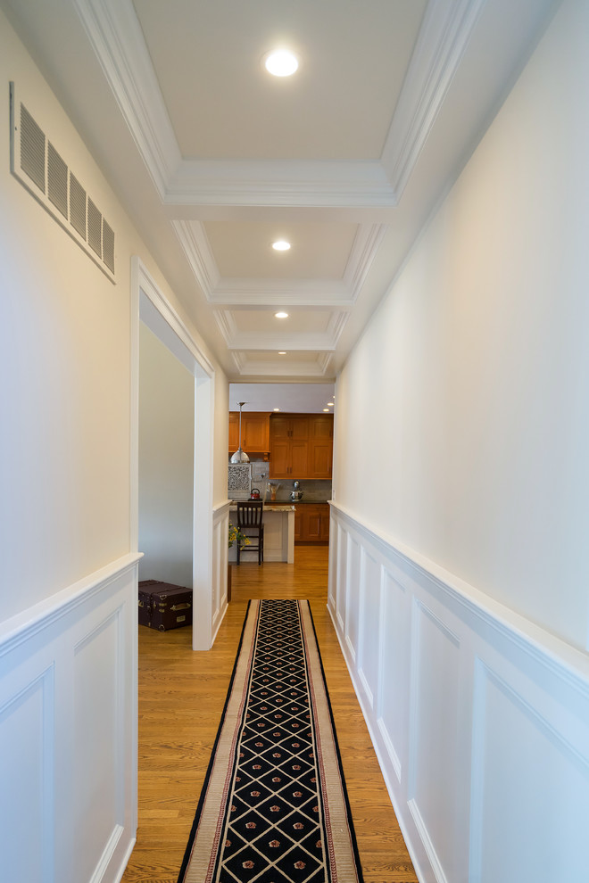 Cette image montre un grand couloir traditionnel avec un mur beige, un sol en bois brun et un sol marron.