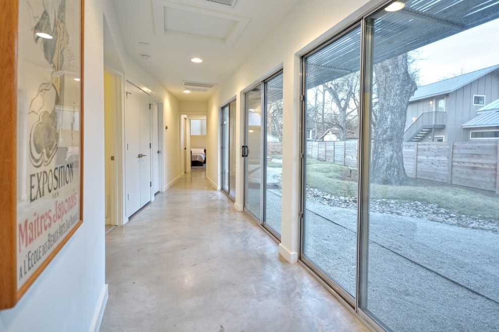 Cette image montre un couloir minimaliste avec un mur beige et sol en béton ciré.