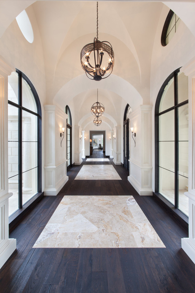 На фото: огромный коридор: освещение в классическом стиле с белыми стенами, темным паркетным полом и разноцветным полом с