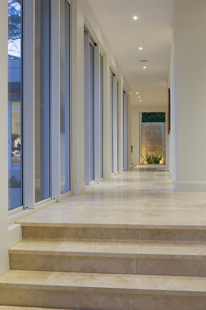 На фото: коридор в стиле неоклассика (современная классика) с белыми стенами и полом из известняка