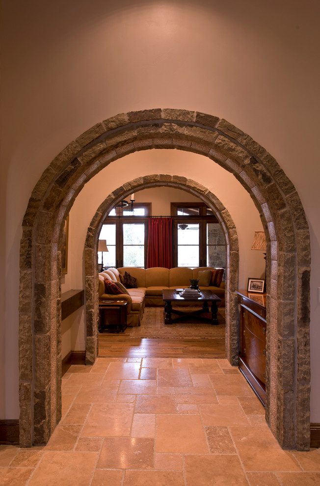 На фото: большой коридор в средиземноморском стиле с бежевыми стенами, полом из известняка и бежевым полом с