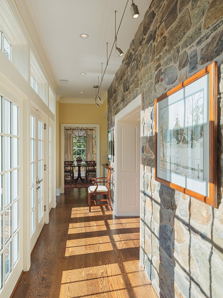 Inspiration pour un couloir traditionnel de taille moyenne avec un mur jaune et un sol en bois brun.