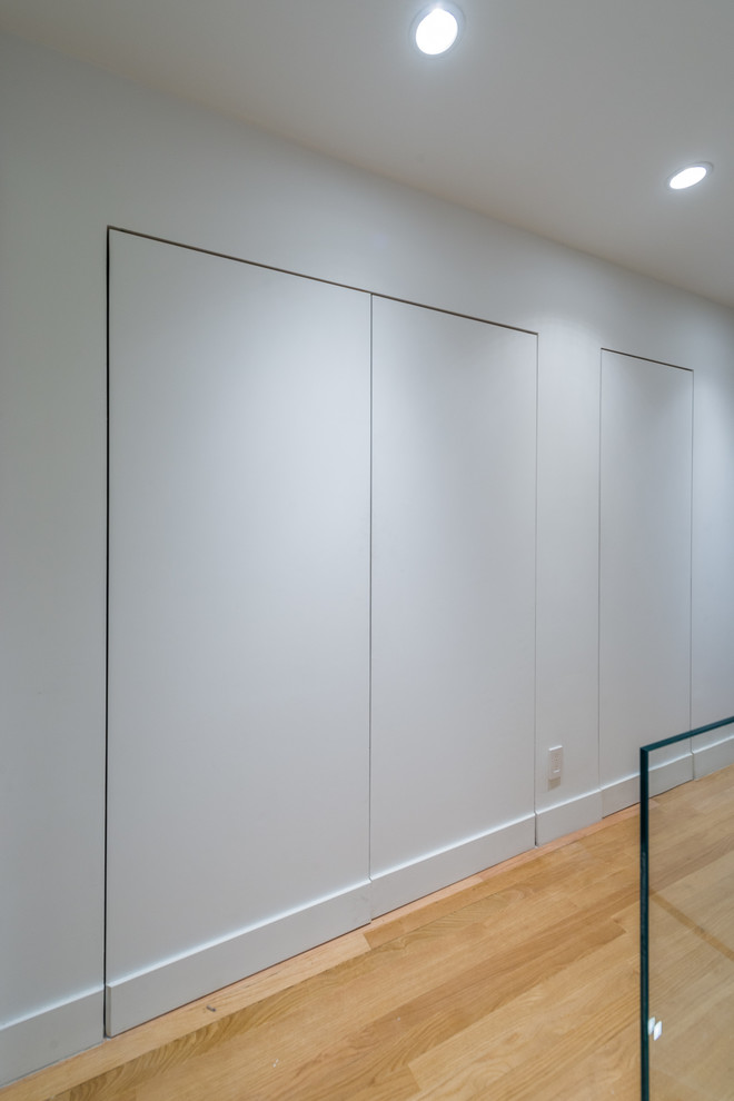 Idee per un piccolo ingresso o corridoio minimalista con pareti bianche e parquet chiaro
