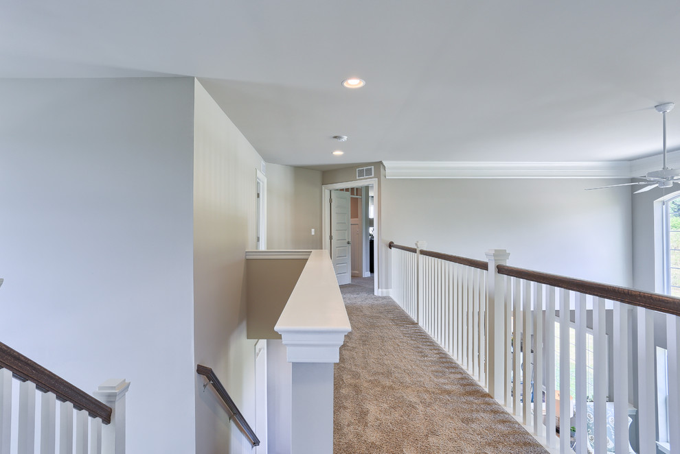 На фото: большой коридор в стиле неоклассика (современная классика) с серыми стенами и ковровым покрытием с