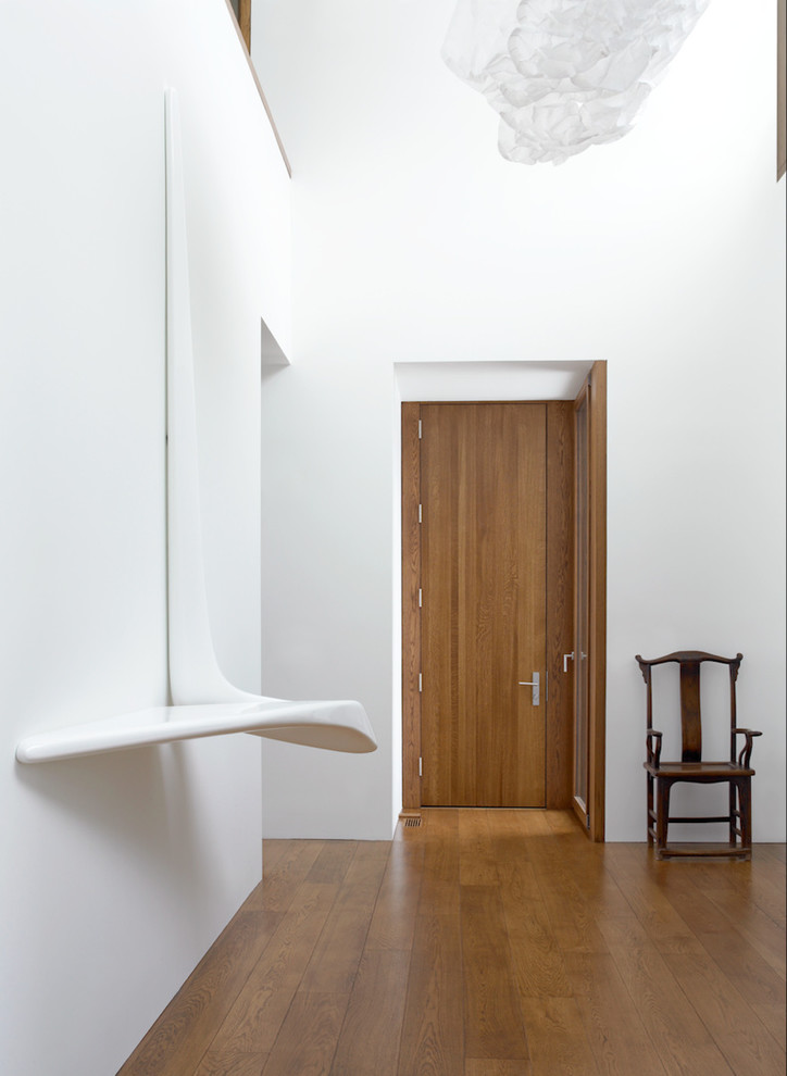 Diseño de recibidores y pasillos contemporáneos grandes con paredes blancas y suelo de madera en tonos medios