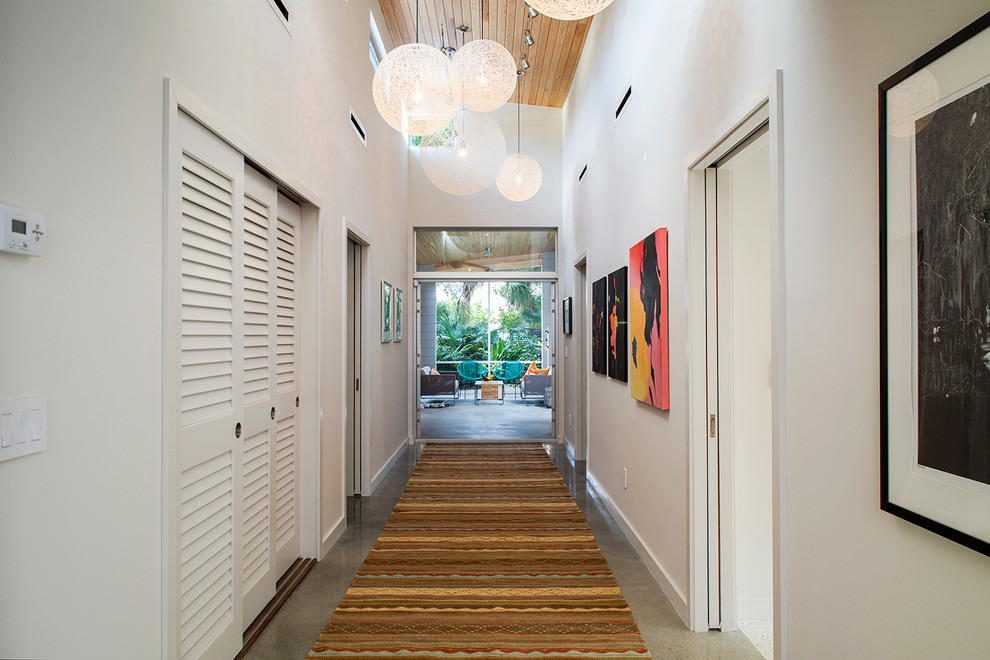 Example of a 1960s concrete floor hallway design in Tampa with white walls