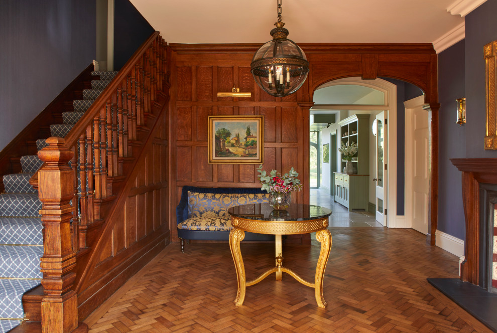Inspiration for a large timeless medium tone wood floor, brown floor and wall paneling hallway remodel in Surrey with blue walls