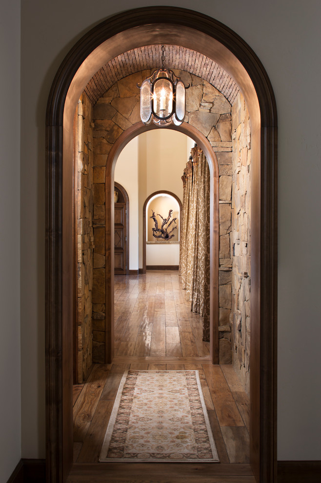 Idée de décoration pour un grand couloir méditerranéen avec un mur beige et un sol en bois brun.