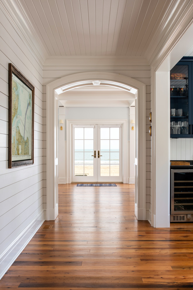 Example of a beach style medium tone wood floor hallway design in Other with white walls