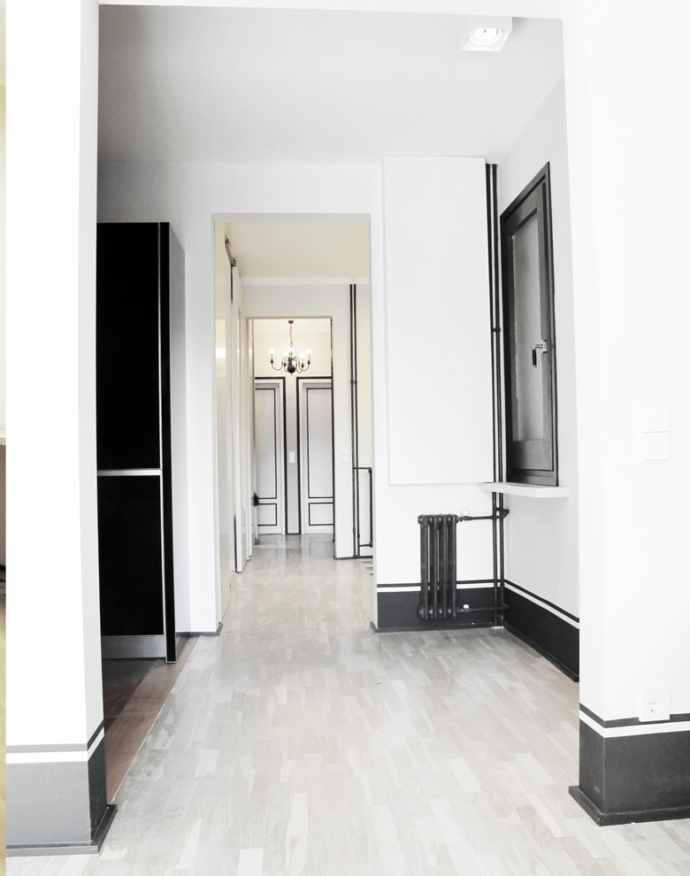 Foto de recibidores y pasillos clásicos renovados de tamaño medio con paredes blancas, suelo de madera clara y suelo marrón