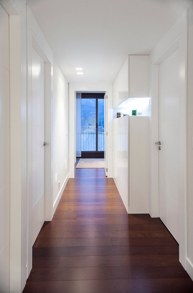 На фото: коридор среднего размера в стиле модернизм с белыми стенами и темным паркетным полом