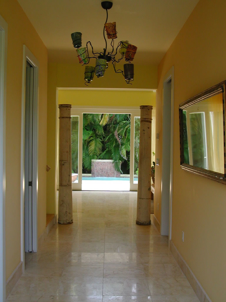 Foto di un ingresso o corridoio tropicale di medie dimensioni con pareti gialle e pavimento in travertino