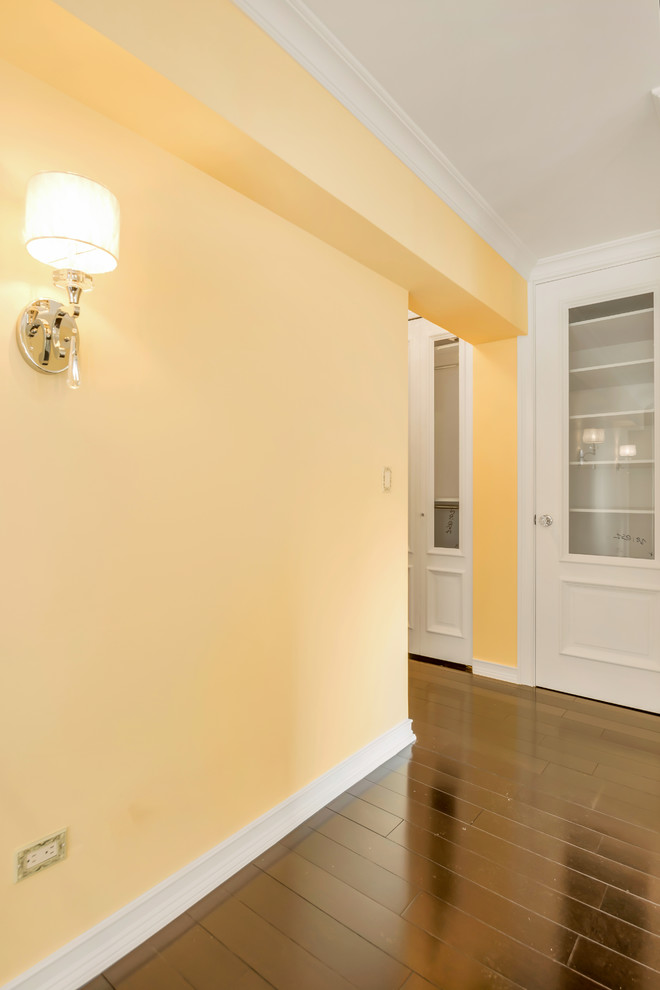 Cette image montre un petit couloir traditionnel avec parquet foncé et un mur jaune.