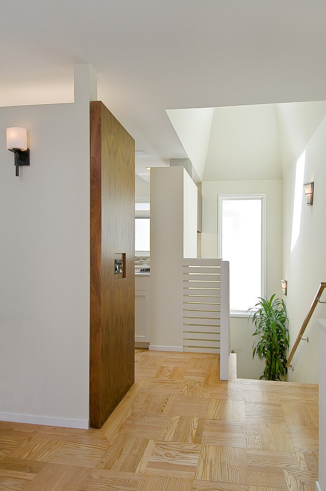 Foto di un ingresso o corridoio minimal con pareti bianche e pavimento in legno massello medio