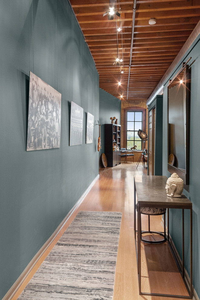 Ejemplo de recibidores y pasillos minimalistas de tamaño medio con paredes verdes, suelo de madera en tonos medios y suelo marrón