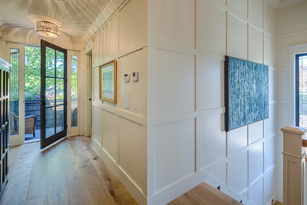 Foto de recibidores y pasillos de estilo americano grandes con paredes blancas y suelo de madera clara